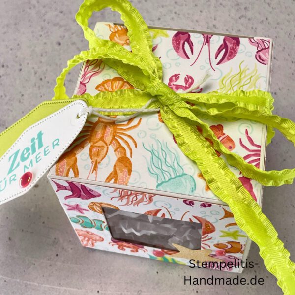Handdekorierte Fensterschachtel 7 cm mit maritimen Motiven, Geschenkbox mit Fenster und Schleife in Grün, Detailansicht Geschenkschachtel Etikett „Zeit für Meer“, Offene Sichtfensterbox von oben, Fensterschachtel mit bunter Meeresdekoration, Geschenkverpackung mit transparentem Fenster, Handgemachte maritime Fensterschachtel mit Schleife